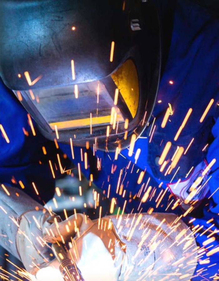 Welder fabricating a steel part with sparks flying
